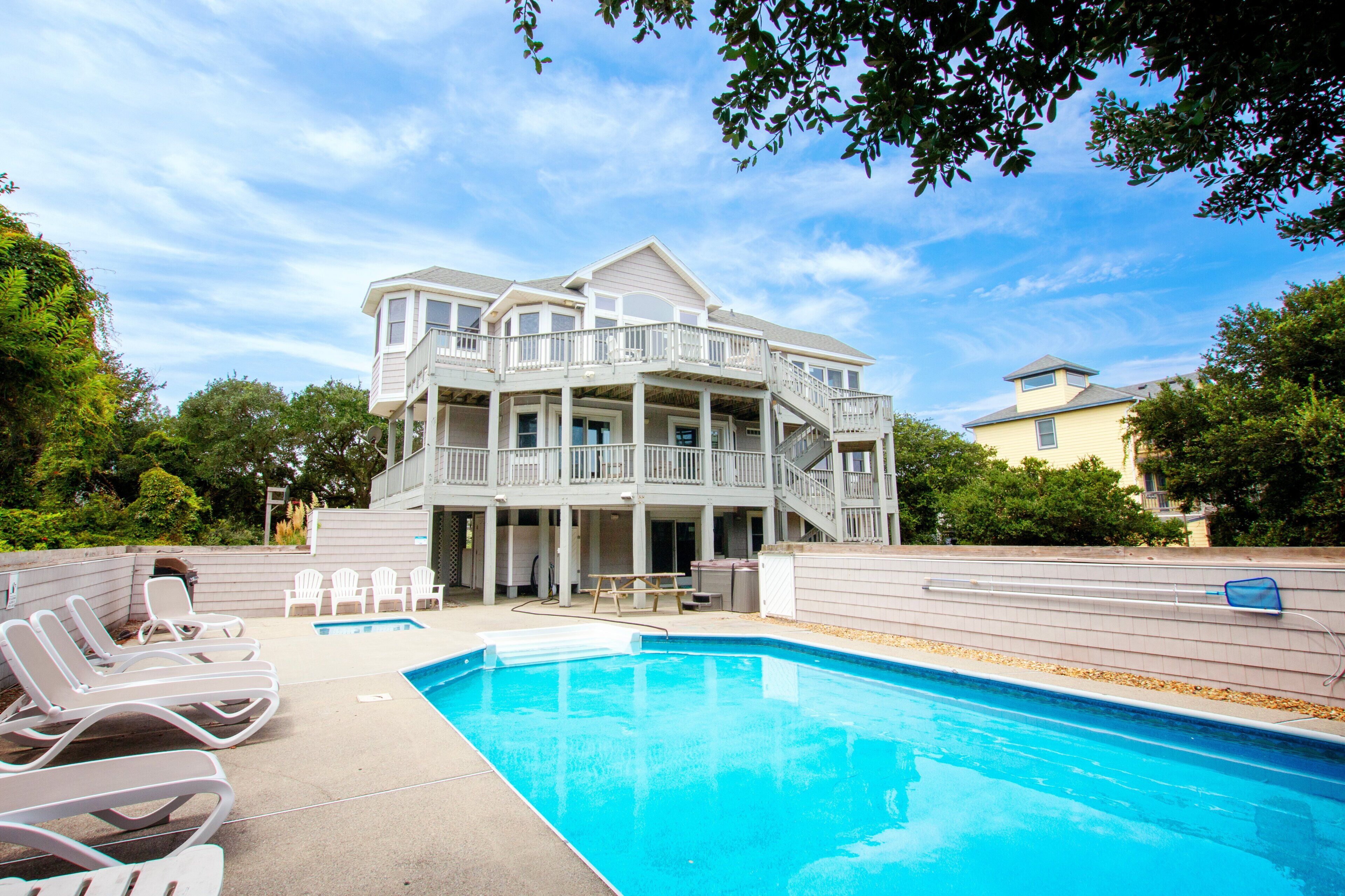 A two-story house with a pool and outdoor seating.