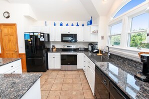 A modern kitchen with white cabinets, a black refrigerator, a microwave, and a stove. - Oceanside, close to beach, Priv. Pool, Hot Tub, Dogs Welcome-  WW1033, Driftwood I (Corolla)