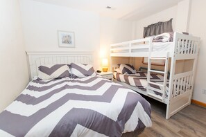 A bunk bed with a striped bedspread, a bedside table with a lamp, and a framed picture on the wall. - Oceanside, close to beach, Priv. Pool, Hot Tub, Dogs Welcome-  WW1033, Driftwood I (Corolla)