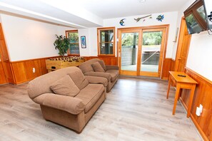 Una sala de estar acogedora con un sofá marrón, una mesa de fútbol y un televisor montado en la pared.
