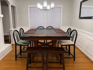 A dining room with a rectangular table, six chairs, a bench, and a chandelier. - Hakuna Matata #6: Home for 12 People - 12 Minutes from Fort Bragg (Fayetteville)