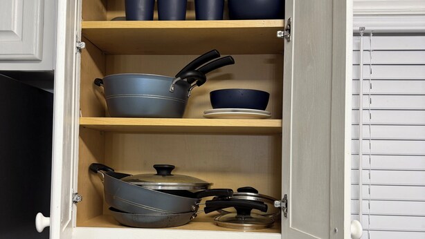 Een keuken met houten planken met kookgerei, een messenblok en een afdruiprek.