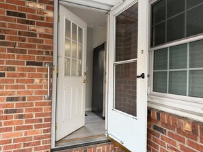 A white door with a glass panel, a metal handle, and a brick wall. - Hakuna Matata #6: Home for 12 People - 12 Minutes from Fort Bragg (Fayetteville)