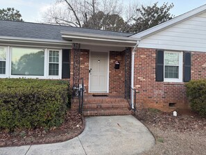 A two-story house with a front porch, a mailbox, and a brick exterior. - Hakuna Matata #6: Home for 12 People - 12 Minutes from Fort Bragg (Fayetteville)