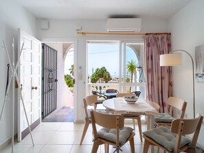 A room with a dining table, chairs, a lamp, and a view of the outside. - Naricha 3 Apartments by Casasol by Interhome (Nerja)