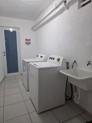 Un lavadero con dos lavadoras y un lavabo.