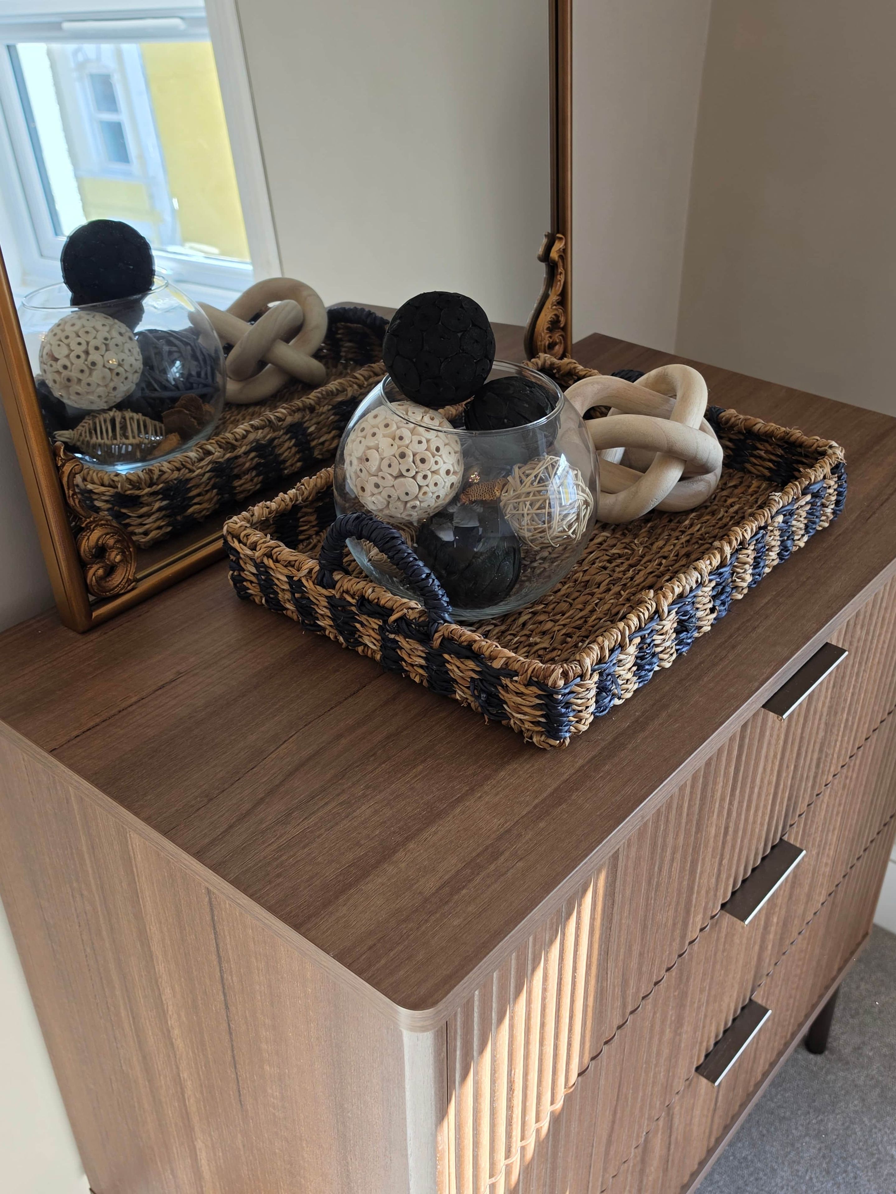A wooden dresser with a woven basket containing decorative items.