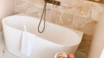Un bagno con una vasca freestanding, un appendi asciugamani e un cesto decorativo con fiori.
