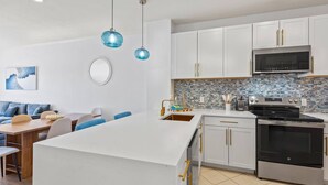 A modern kitchen with white cabinets, a stainless steel stove, and a tiled backsplash. - Steps To The Beach-Pet Friendly-Pool-EW303 (Miramar Beach)