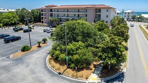 A multi-story parking structure with a landscaped area featuring trees and shrubs. - Steps To The Beach-Pet Friendly-Pool-EW303 (Miramar Beach)