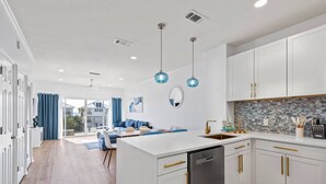 A modern kitchen with white cabinetry, a dishwasher, and a blue pendant light. - Steps To The Beach-Pet Friendly-Pool-EW303 (Miramar Beach)