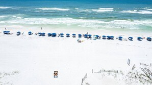 A beach with white sand and a row of blue umbrellas. - Steps To The Beach-Pet Friendly-Pool-EW303 (Miramar Beach)