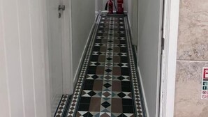 A narrow hallway with patterned flooring leading to a door.