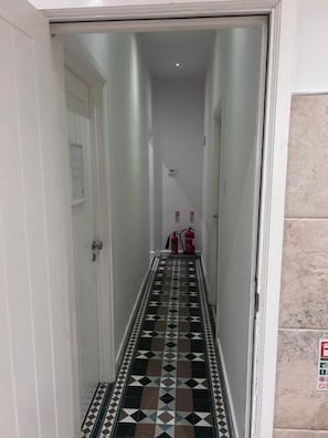 A narrow hallway with patterned flooring leading to a door.