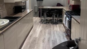 A modern kitchen with a central island, bar stools, and a built-in oven.