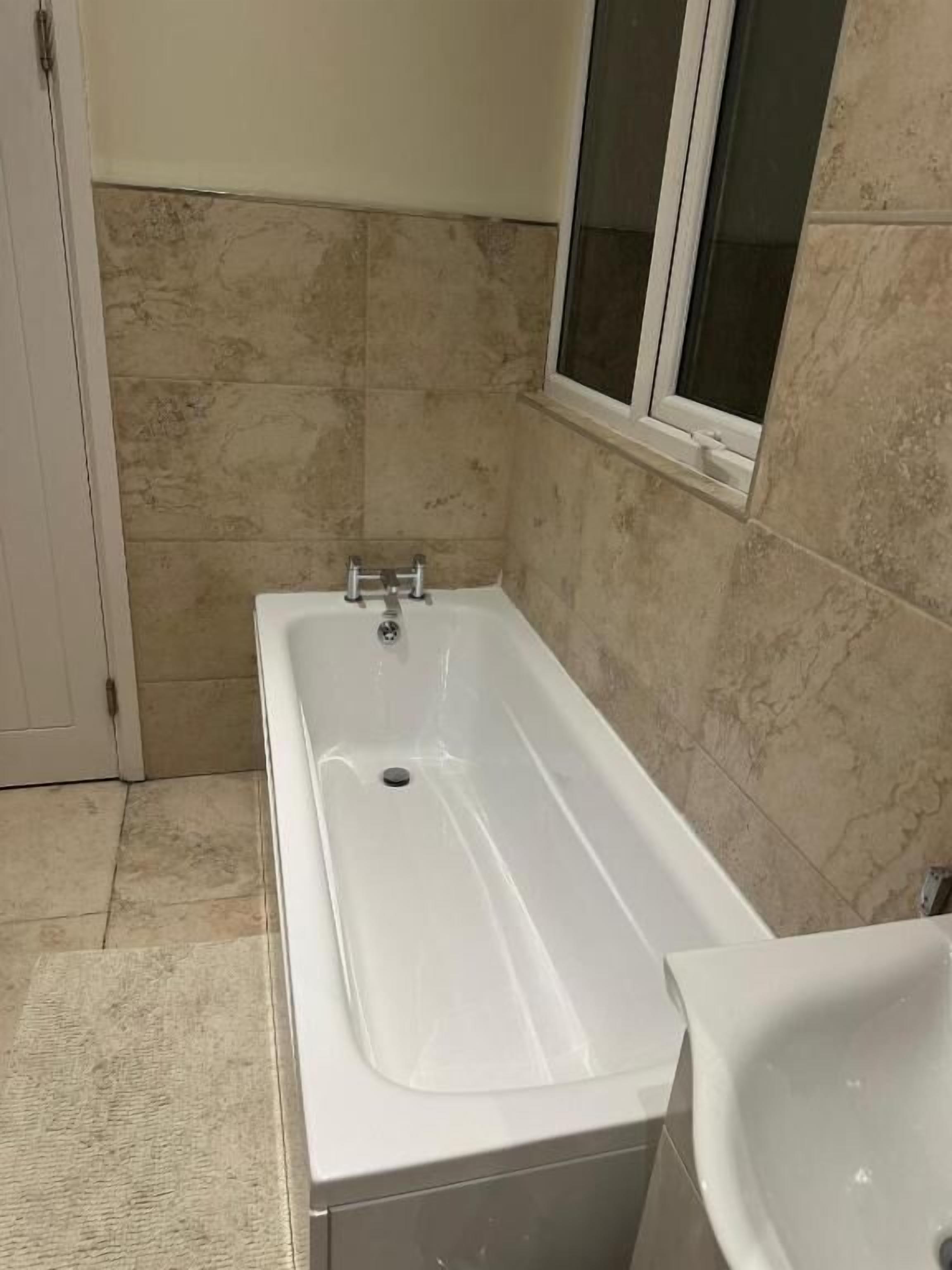 A bathroom with a bathtub, a sink, and a window.