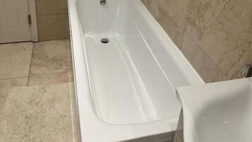 A bathroom with a bathtub, a sink, and a window.
