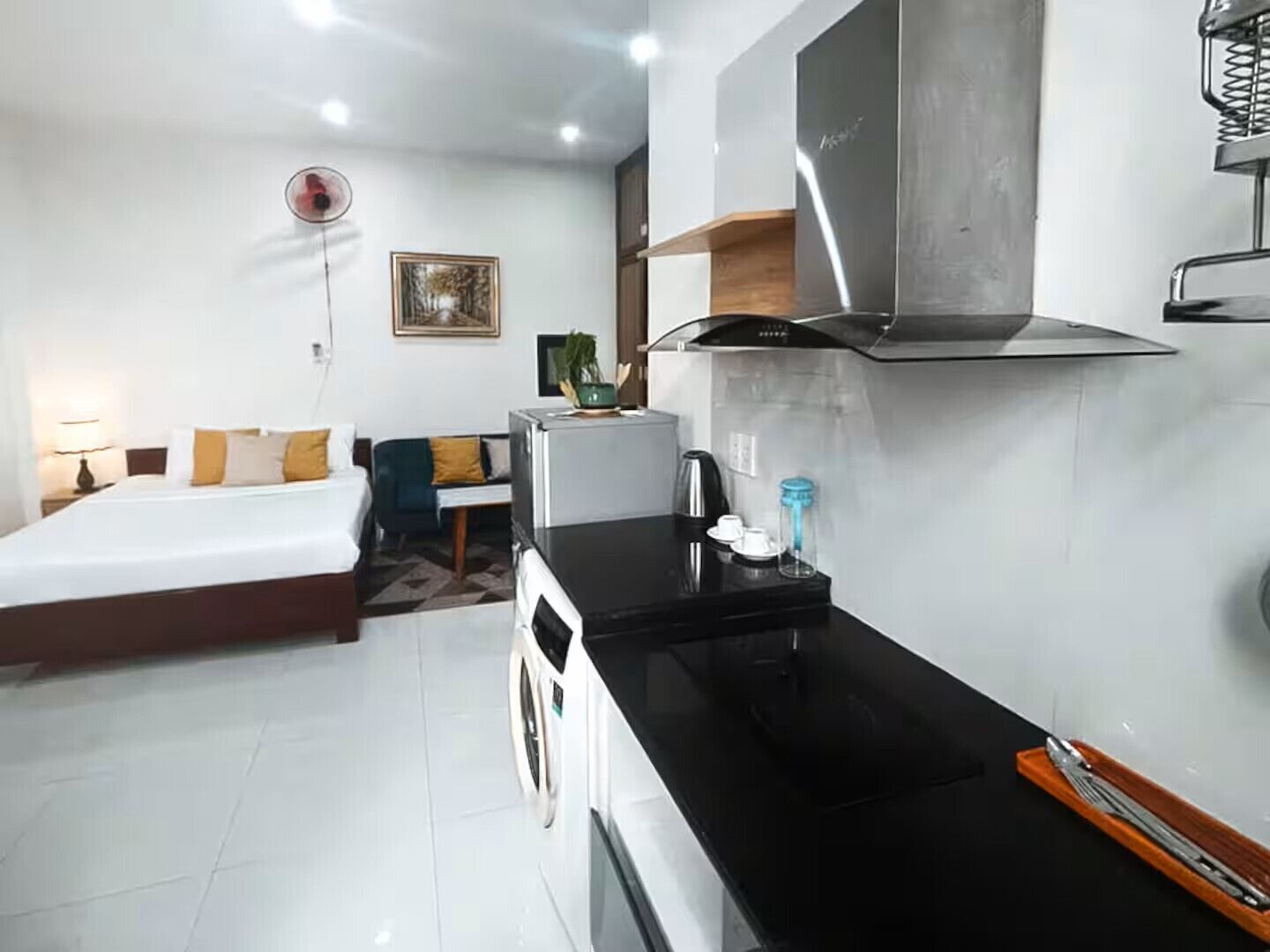 A compact hotel room with a bed, a small kitchenette, and a dining area.