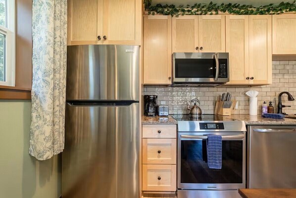 A modern kitchen with stainless steel appliances, wooden cabinets, and a tiled backsplash.