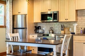 A modern kitchen with stainless steel appliances, a central island, and light wood cabinetry.