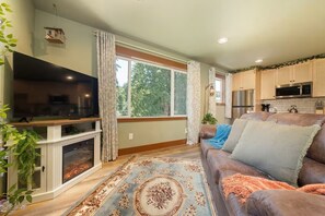 A living room with a fireplace, television, and a large window.