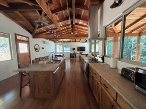 A spacious kitchen with wooden beams, a large island, and a view of the outdoors.