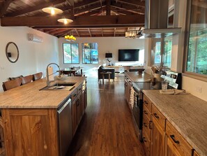 A spacious kitchen with wooden cabinets, a central island, and a dining area with a table and chairs. - Brand New custom built 2 bedroom home in Hiouchi near Stout Grove/Titan Trail (Hiouchi)