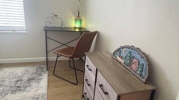 A room with a desk, chair, and a dresser with drawers.