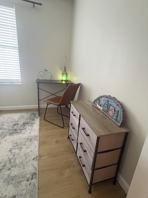 A room with a desk, chair, and a dresser with drawers.