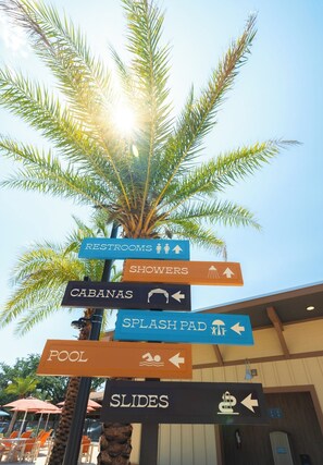 A directional signpost with multiple arrows pointing to amenities such as restrooms, showers, cabanas, splash pad, pool, and slides. - Luxury River Ranch RV w/ Pavilion Lot & views! 161 (River Ranch)