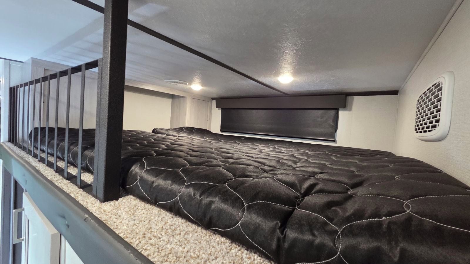 A bedroom with a bed, a headboard, a window, and a staircase.