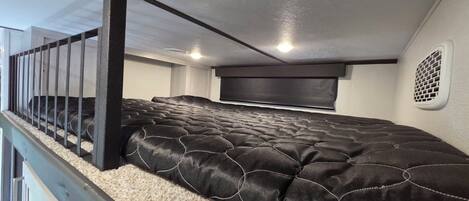 A bedroom with a bed, a headboard, a window, and a staircase.