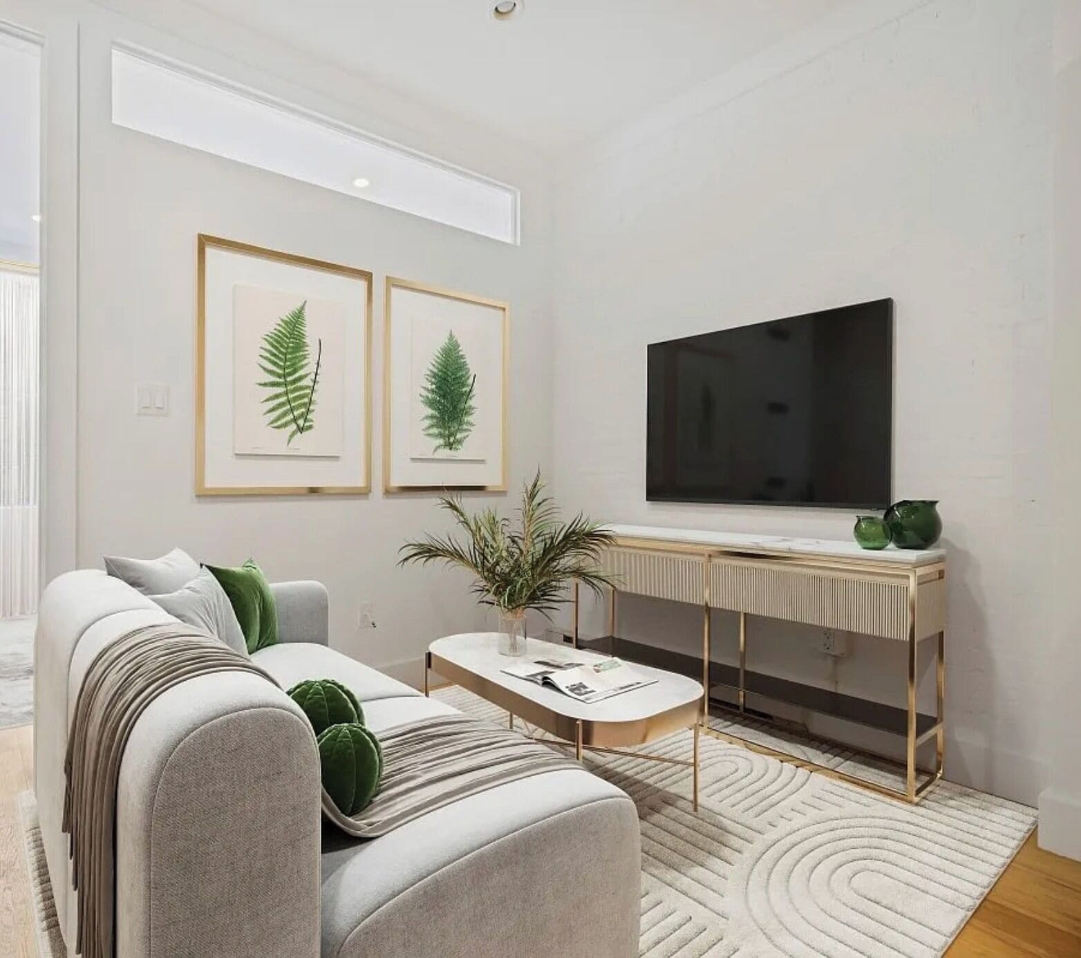 A modern living room with a sofa, coffee table, and a flat-screen TV mounted on the wall.