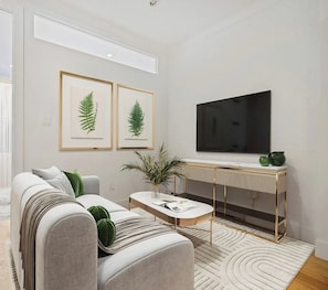 A modern living room with a sofa, coffee table, and a flat-screen TV mounted on the wall.