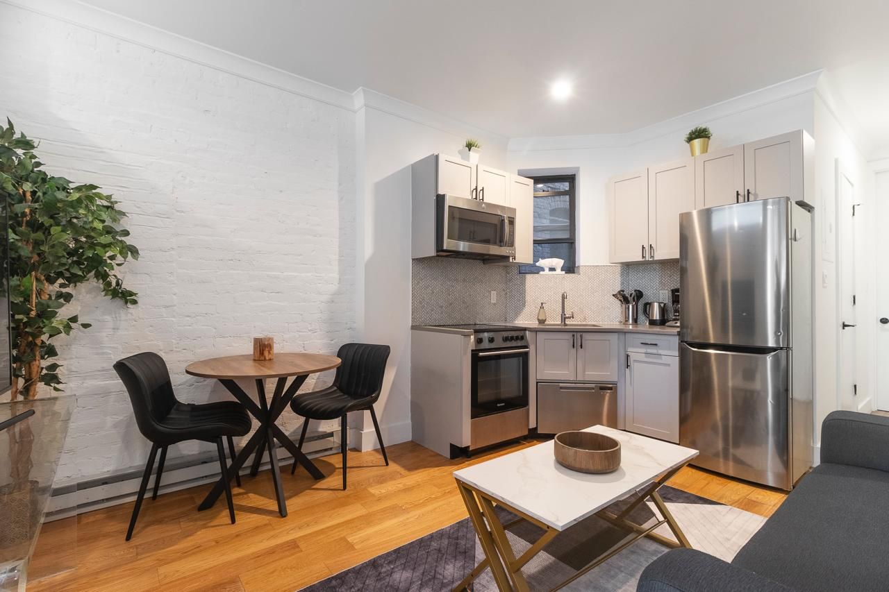 A compact kitchen with modern appliances, a dining area with two chairs, and a small table.