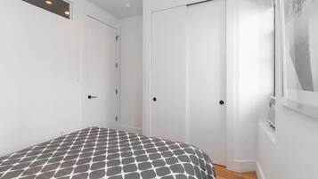 Un dormitorio con cama, dos puertas blancas y un radiador.