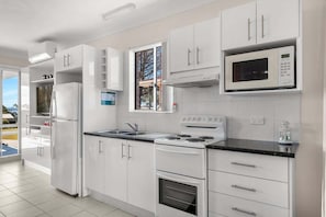 A modern kitchen with white cabinetry, a built-in microwave, a stove, and a refrigerator.