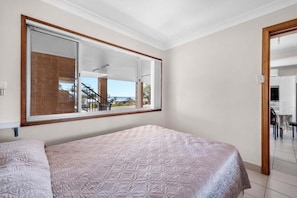 A bedroom with a large window, a bed, and a view of the outside.