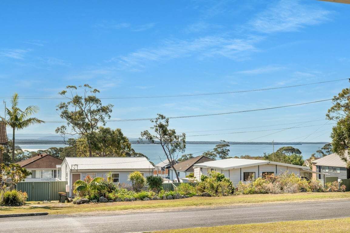 A coastal residential area with houses, a clear sky, and a view of the sea.