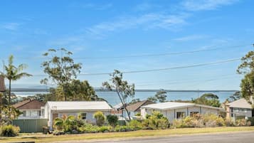 A coastal residential area with houses, a clear sky, and a view of the sea.