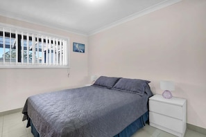 A bedroom with a bed, nightstand, and window.