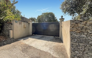 A gated entrance with a stone wall and a metal gate, a mailbox, and a number sign. - Nice home in Nîmes with swimming pool (Nîmes)