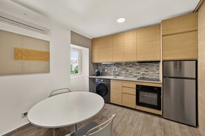 A modern kitchen with wooden cabinets, a stainless steel refrigerator, a built-in oven, and a washing machine. - Setúbal Arena III, By Home Match (Setúbal)