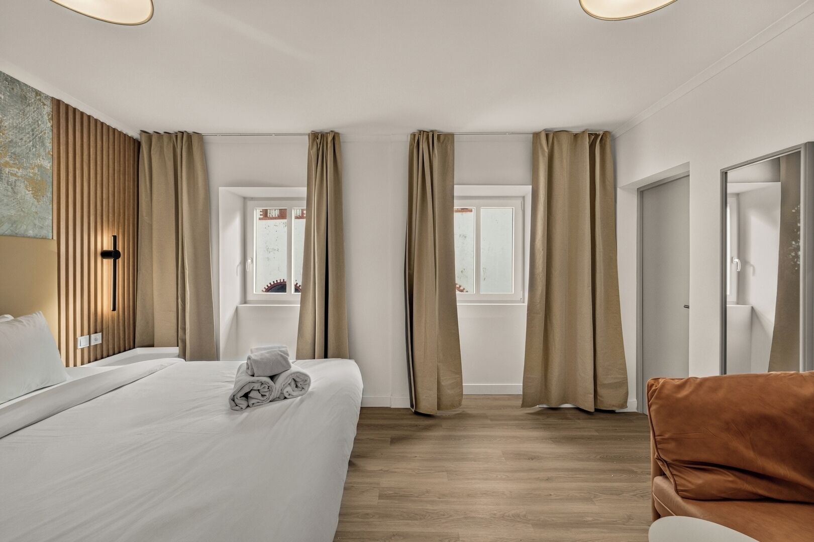 Una habitación de hotel con cama, una silla, un ventanal y una puerta.