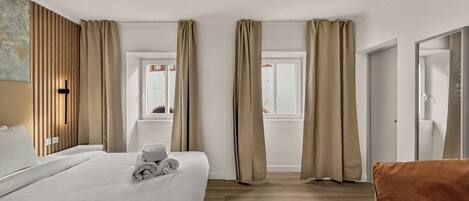 A hotel room with a bed, a chair, a window, and a door.