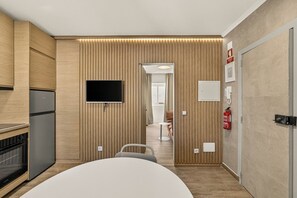 A modern kitchen with built-in appliances, a flat-screen TV, and a wooden accent wall. - Setúbal Arena III, By Home Match (Setúbal)