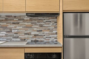 A kitchen with a stone backsplash, stainless steel appliances, and wooden cabinetry. - Setúbal Arena III, By Home Match (Setúbal)