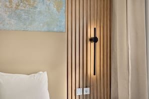 A hotel room with a wooden panel wall, a black handle, a white pillow, and a painting. - Setúbal Arena III, By Home Match (Setúbal)