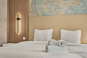 A hotel room with a bed, two pillows, a wall-mounted light, and a textured wall art piece. - Setúbal Arena III, By Home Match (Setúbal)