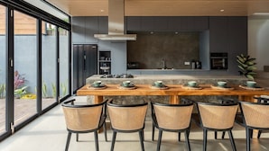 Una cocina moderna con una isla central, sillas negras y una mesa de comedor.